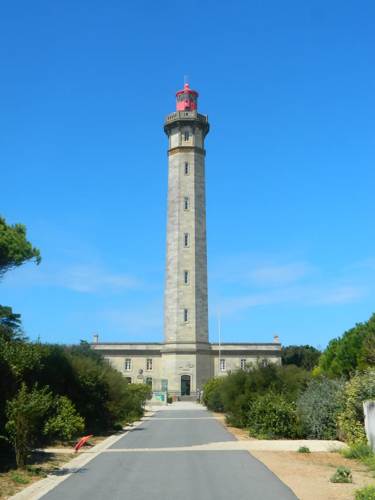 Le phare des Baleines vu de face : la tour de pierre, sa lanterne rouge, ciel bleu